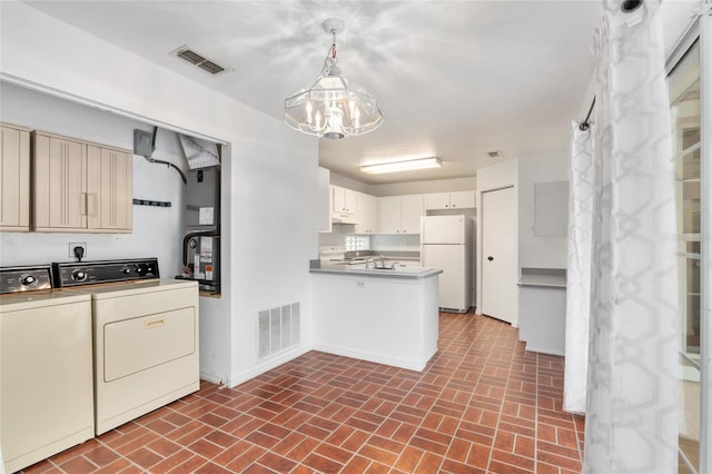 kitchen with white appliances, hanging light fixtures, a notable chandelier, and washer and clothes dryer