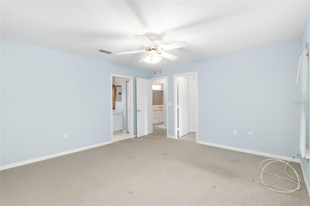 unfurnished bedroom with electric panel, ceiling fan, light colored carpet, and ensuite bath