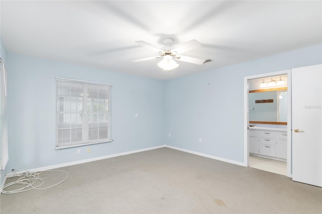 unfurnished bedroom featuring light colored carpet, ensuite bath, and ceiling fan