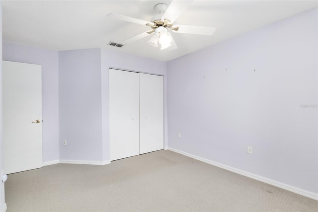 unfurnished bedroom featuring ceiling fan, light colored carpet, and a closet