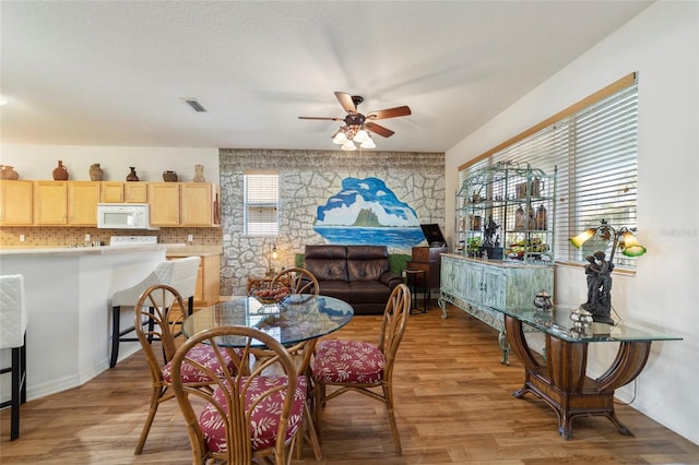 dining space with ceiling fan and light hardwood / wood-style flooring