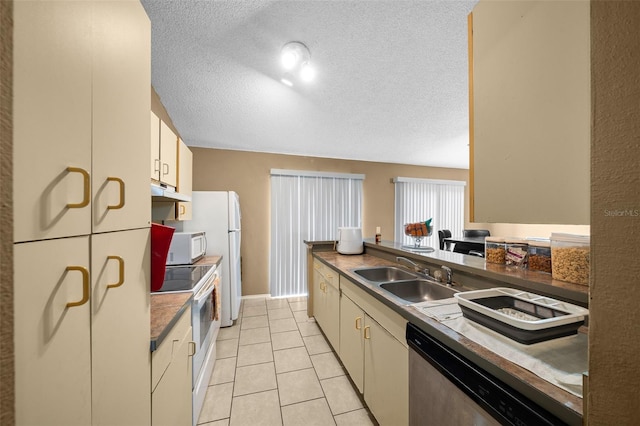 kitchen featuring cream cabinets, sink, light tile patterned flooring, a textured ceiling, and white appliances