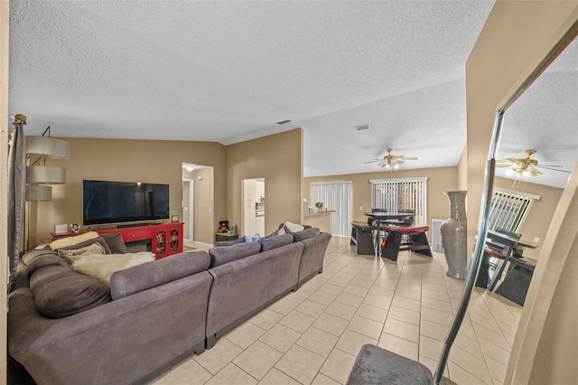 tiled living room featuring ceiling fan, a textured ceiling, and lofted ceiling