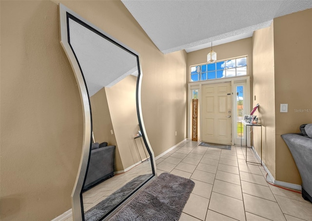 foyer featuring a notable chandelier, a textured ceiling, a high ceiling, and light tile patterned floors