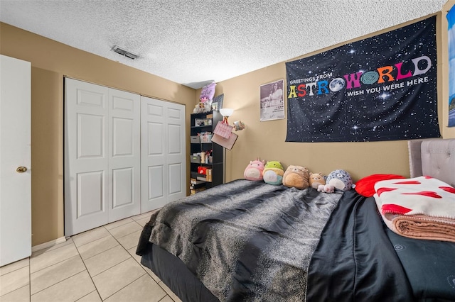 bedroom featuring a closet, a textured ceiling, and light tile patterned flooring