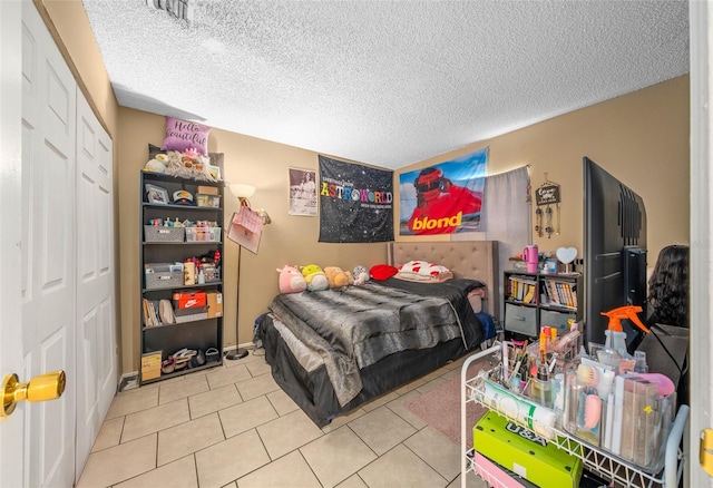 bedroom with a closet, a textured ceiling, and light tile patterned floors