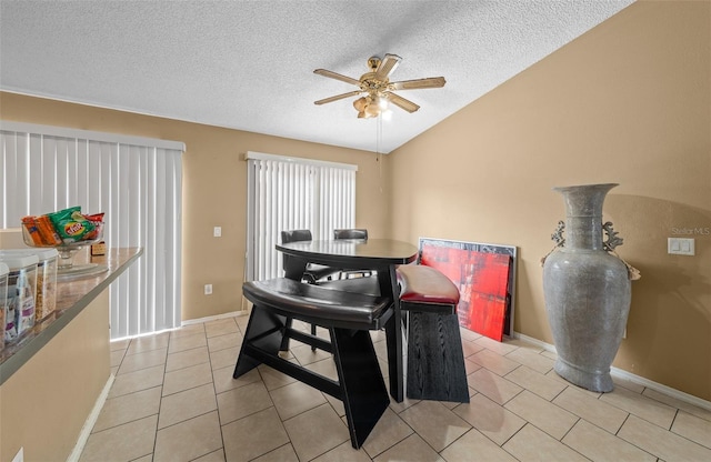 dining area with a textured ceiling, ceiling fan, light tile patterned floors, and vaulted ceiling