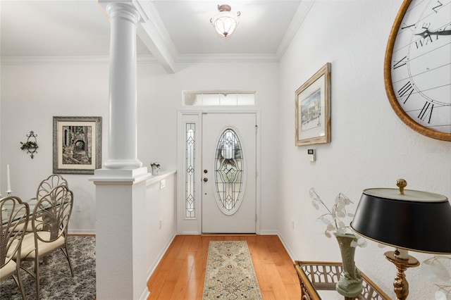 foyer entrance with ornamental molding, hardwood / wood-style flooring, and decorative columns