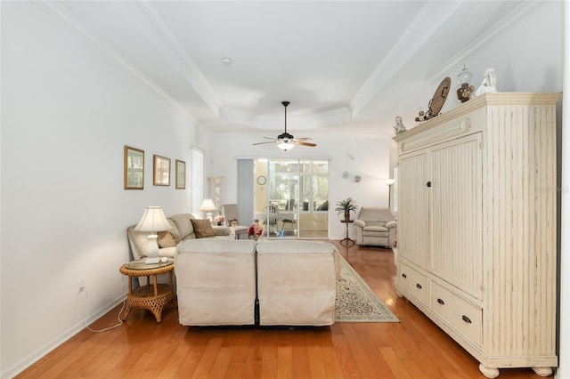 living room featuring crown molding, a tray ceiling, ceiling fan, and light hardwood / wood-style flooring