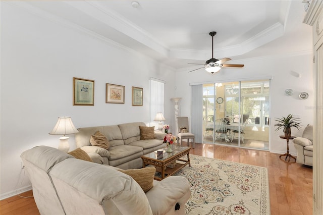 living room featuring ceiling fan, a tray ceiling, crown molding, and light hardwood / wood-style floors