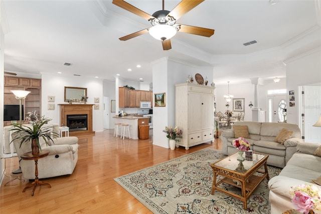 living room with ornamental molding, ceiling fan, and light hardwood / wood-style flooring