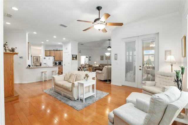 living room with light wood-type flooring, crown molding, ceiling fan, and french doors