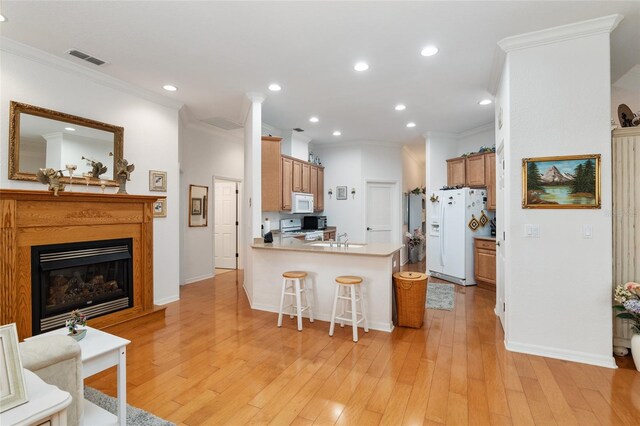 kitchen with light hardwood / wood-style floors, a breakfast bar, white appliances, kitchen peninsula, and ornamental molding