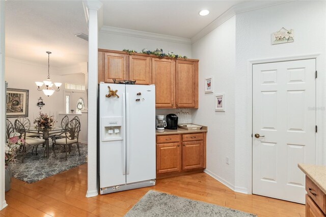 kitchen featuring pendant lighting, white fridge with ice dispenser, light hardwood / wood-style floors, an inviting chandelier, and crown molding