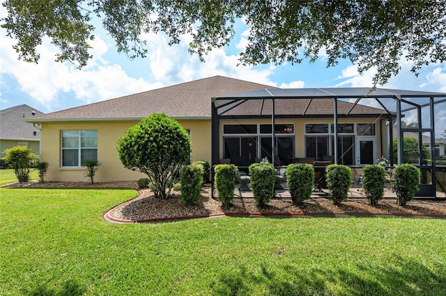 back of property with a lawn, glass enclosure, and a patio area