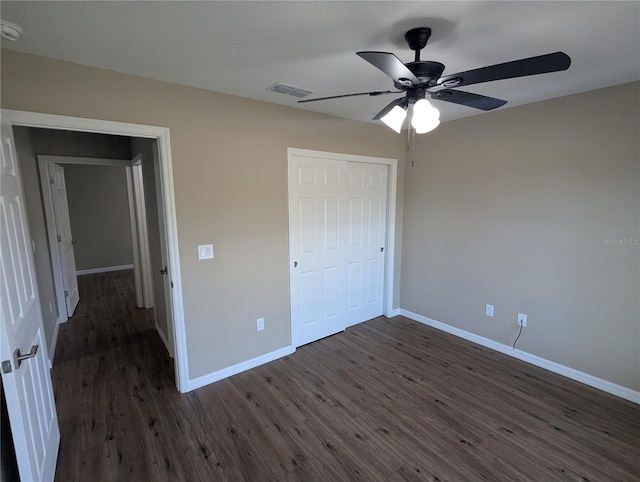 unfurnished bedroom with dark hardwood / wood-style flooring, a closet, and ceiling fan