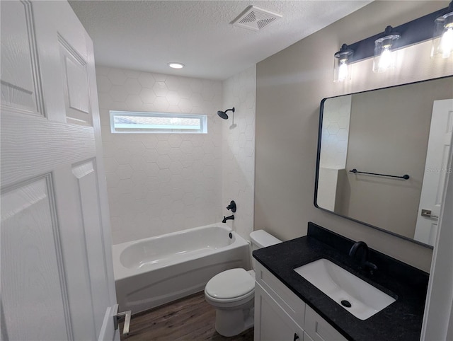 full bathroom with vanity, tiled shower / bath, toilet, a textured ceiling, and wood-type flooring