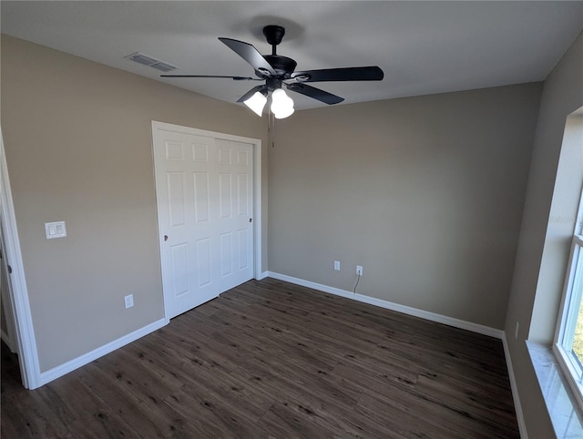 unfurnished bedroom featuring ceiling fan, a closet, and dark wood-type flooring