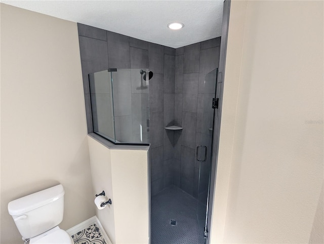 bathroom featuring a shower with shower door and toilet