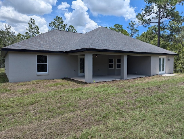 rear view of property featuring a lawn, a patio, and french doors