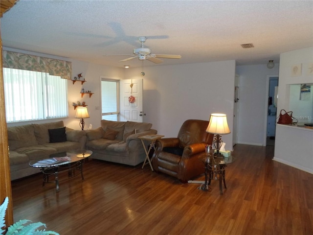 living room with a textured ceiling, dark hardwood / wood-style floors, and ceiling fan