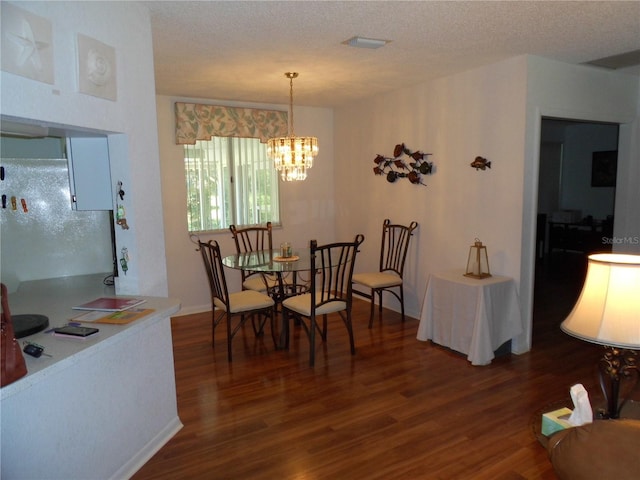 dining area with a textured ceiling, dark hardwood / wood-style floors, and a chandelier