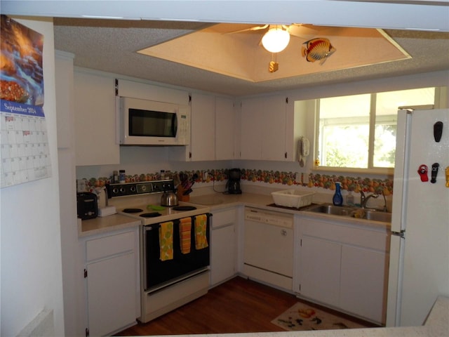 kitchen with white appliances, white cabinetry, sink, and dark hardwood / wood-style flooring