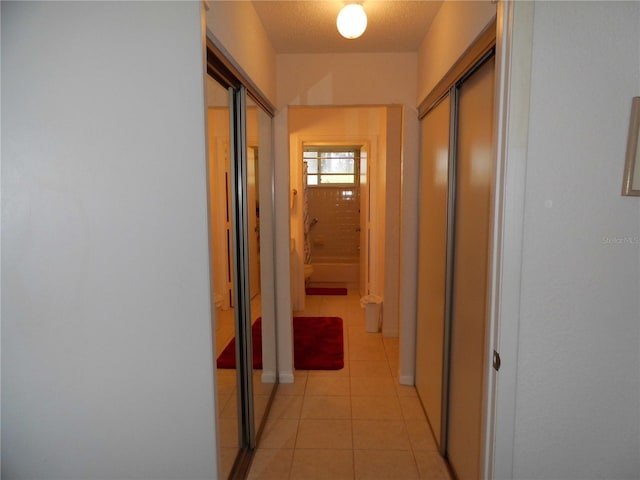 corridor with a textured ceiling and light tile patterned flooring