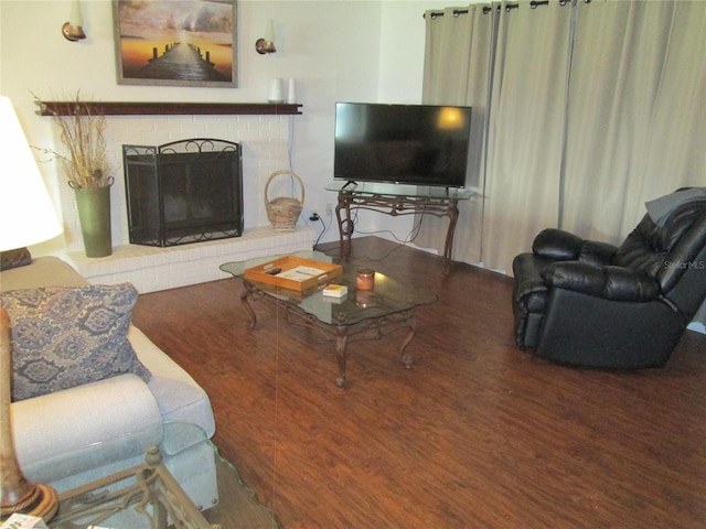 living room with a brick fireplace and dark hardwood / wood-style flooring