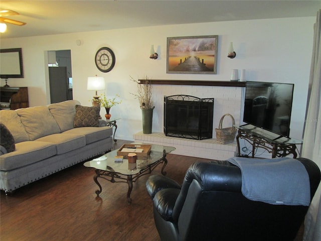 living room featuring ceiling fan, hardwood / wood-style flooring, and a brick fireplace