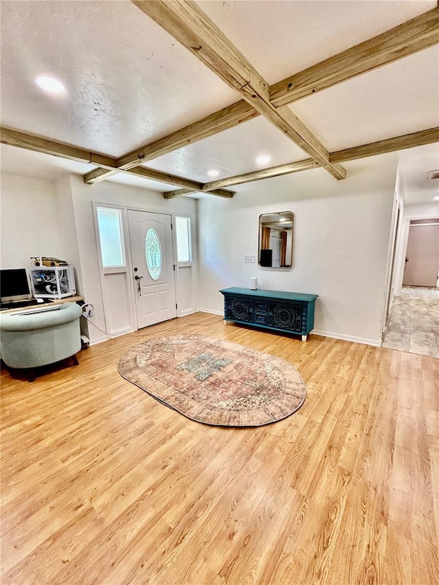 foyer entrance featuring beam ceiling, a textured ceiling, and light wood-type flooring