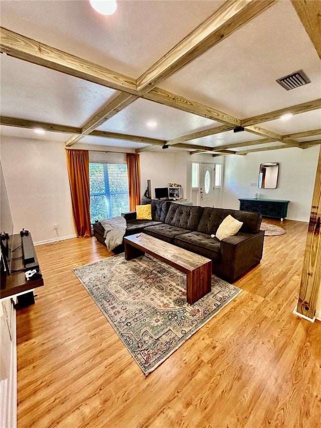 living room with beam ceiling, a textured ceiling, and light wood-type flooring