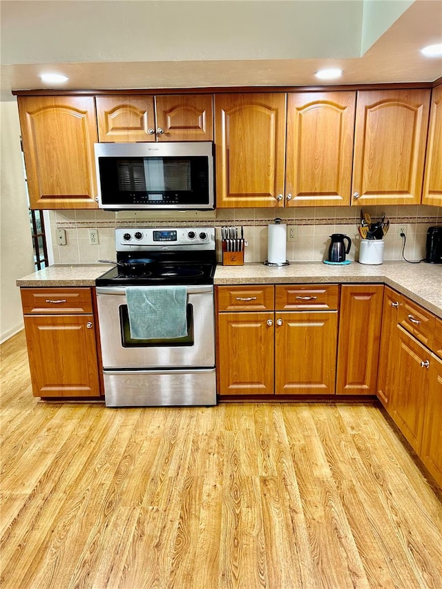 kitchen with backsplash, stainless steel appliances, and light hardwood / wood-style floors