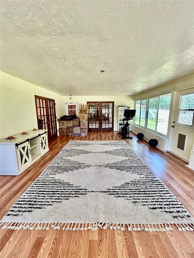 unfurnished living room with french doors, a textured ceiling, and hardwood / wood-style flooring