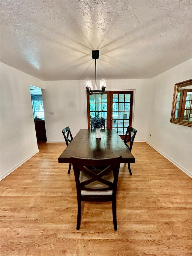 dining space with a chandelier, a textured ceiling, and light hardwood / wood-style flooring