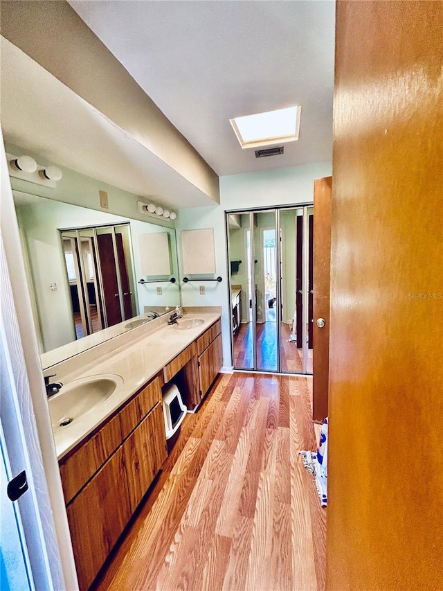 bathroom featuring a skylight, vanity, and wood-type flooring