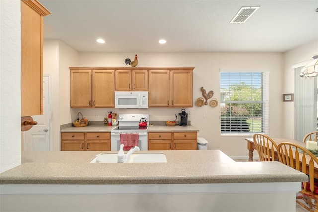 kitchen with kitchen peninsula, sink, and white appliances