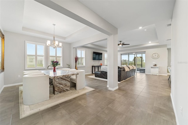 dining space featuring a tray ceiling, tile patterned flooring, and ceiling fan with notable chandelier