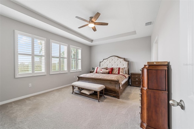 bedroom featuring a raised ceiling, ceiling fan, and light carpet