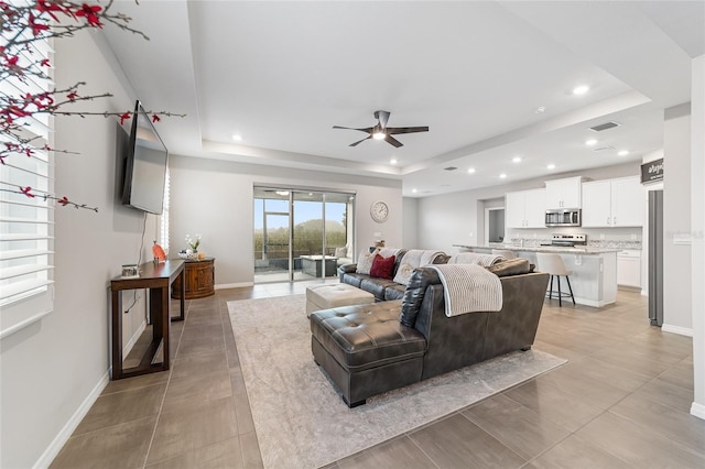 living room featuring a raised ceiling and ceiling fan