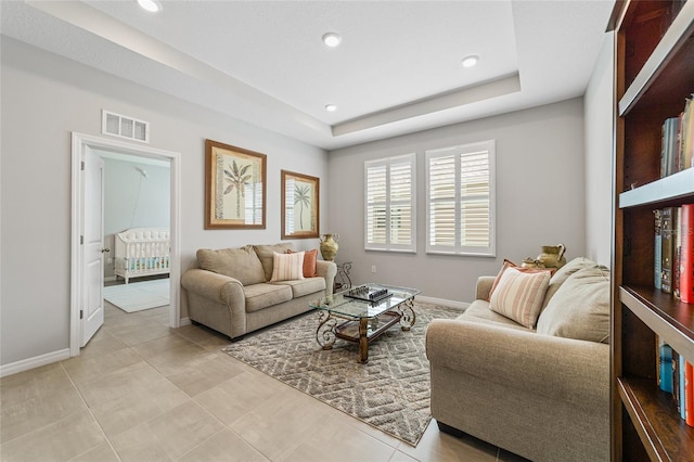 living room featuring a raised ceiling and light tile patterned floors