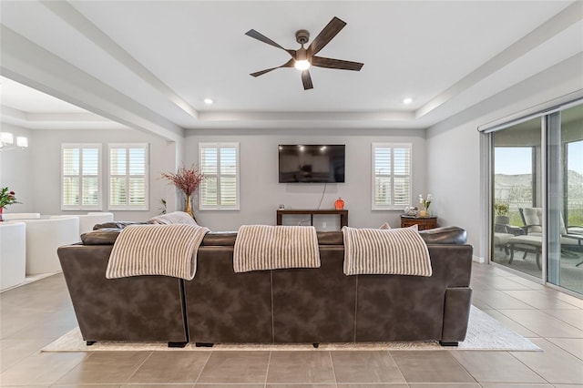 tiled living room featuring a raised ceiling and ceiling fan