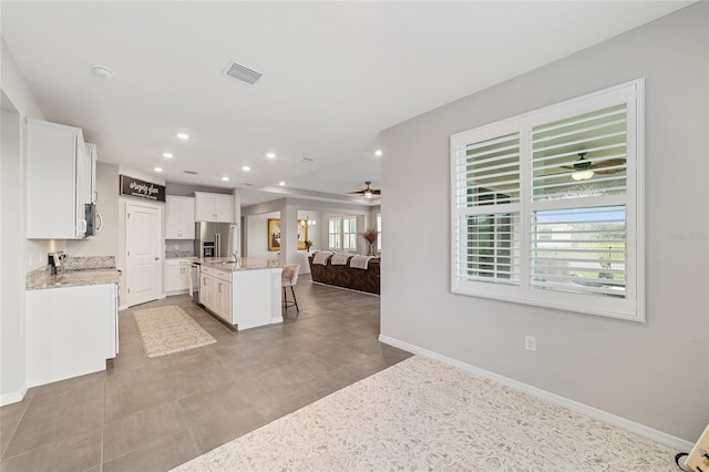 kitchen featuring a breakfast bar, white cabinetry, an island with sink, and stainless steel appliances