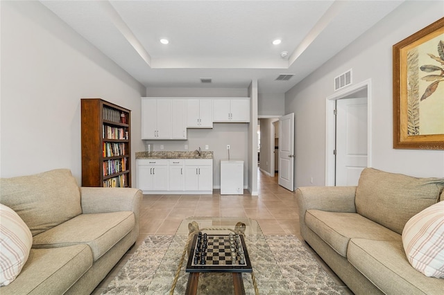 tiled living room featuring a tray ceiling