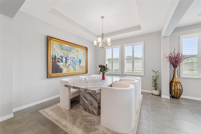 tiled dining room featuring a raised ceiling and a notable chandelier