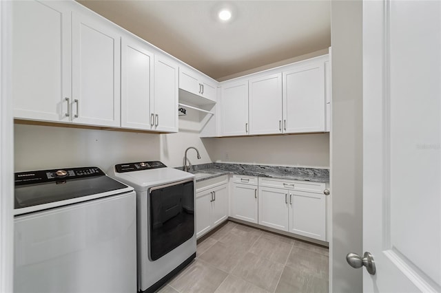 clothes washing area featuring cabinets, light tile patterned flooring, washer and clothes dryer, and sink