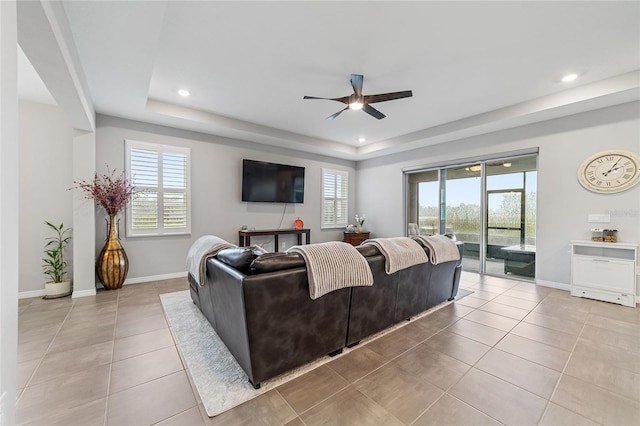 living room featuring ceiling fan, light tile patterned floors, and a tray ceiling