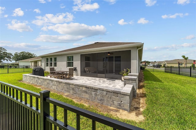 rear view of property featuring a sunroom, a patio area, and a lawn