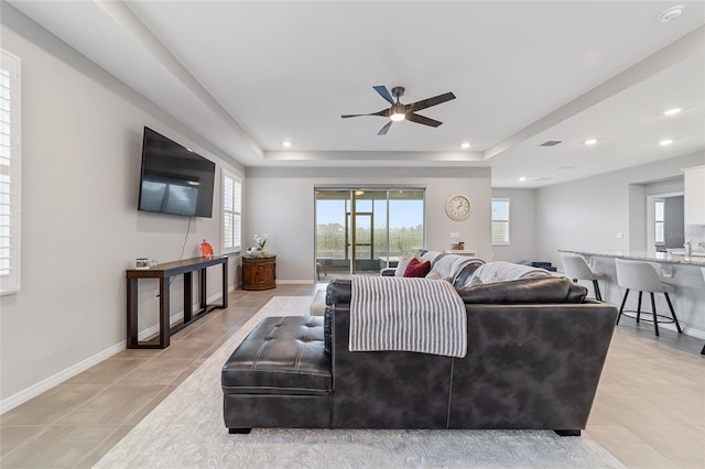 living room with ceiling fan, light tile patterned flooring, and a raised ceiling