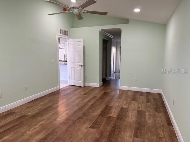 spare room featuring lofted ceiling, dark wood-type flooring, and ceiling fan